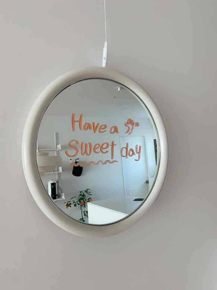 White-toned kitchen space featuring a central round wall mirror and plant with a clean, minimalistic interior