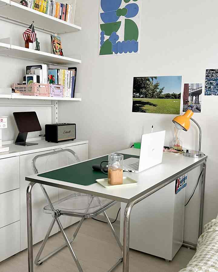 White and green toned home office featuring a desk, transparent chair, and retro Marshall speaker in a clean workspace