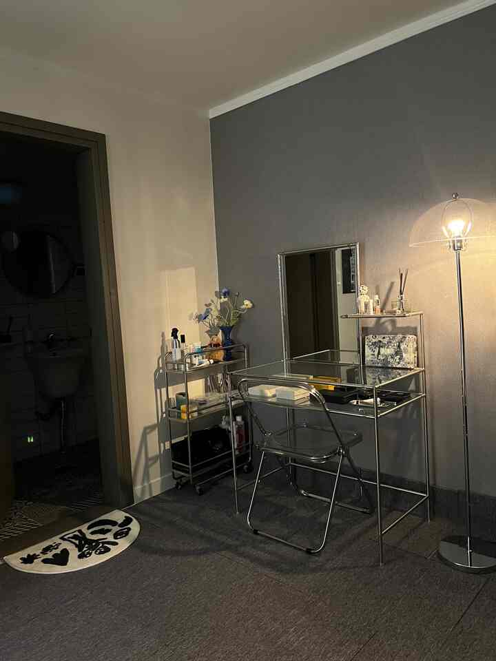 Small room in dark gray and white tones featuring metal frame vanity and floor lamp with a modern atmosphere