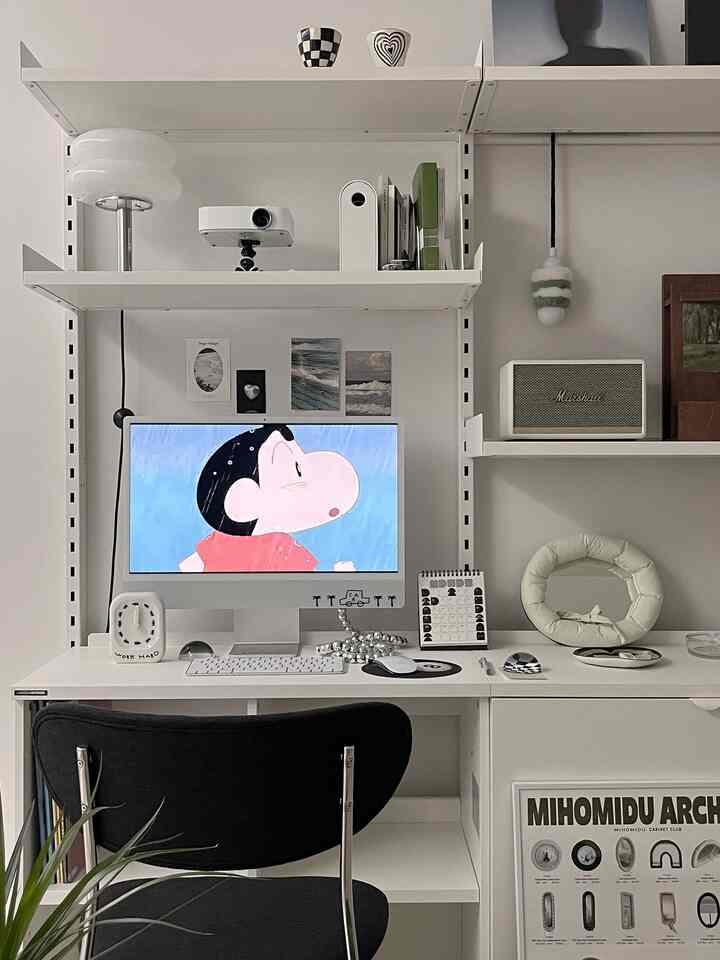 White-toned home office featuring system shelves and an iMac desk, creating a clean and modern workspace