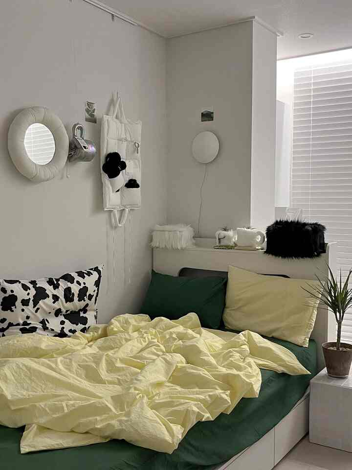 White and green toned bedroom with yellow duvet cover and black patterned cushion in a natural modern space