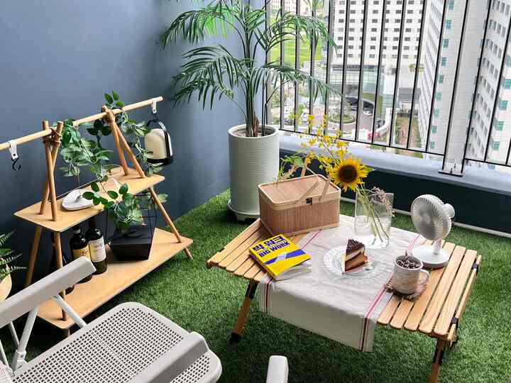 緑の人工芝とベージュの木目調が特徴的なテラス、屋外テーブルと植物が配置された雰囲気のあるおうちカフェ空間