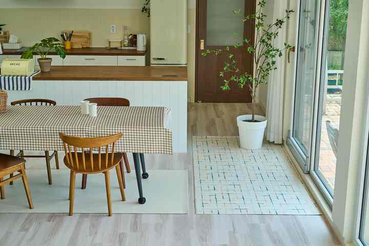 ベージュと木目調の調和が取れたダイニングルームとキッチン、大きな食卓とテーブルクロス、植物が配置された自然な雰囲気のインテリア