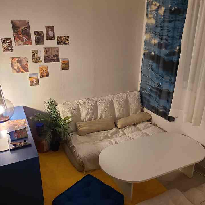 ホワイトとブルーの色調のリビング、ソファベッドとコーヒーテーブルが配置された落ち着いた空間