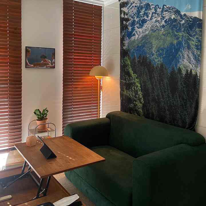 Natural modern living room with dark green sofa, wooden coffee table, and wooden blinds creating a warm atmosphere