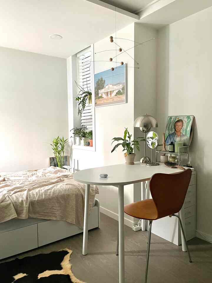 White and brown toned bedroom featuring a simple desk and chair in a cozy single household space