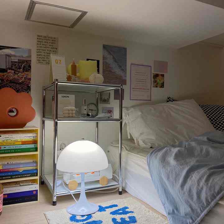 A white and blue tone bedroom featuring a simple bed, metal nightstand, and rounded table lamp creating a cozy atmosphere