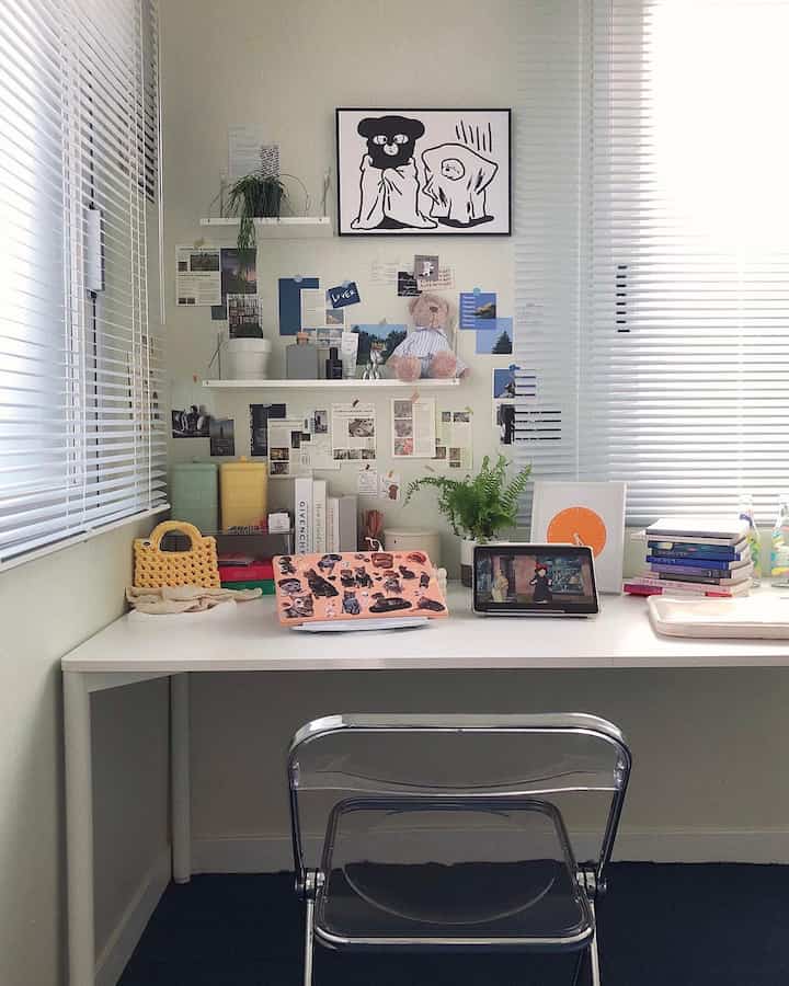 Bright white toned home office space featuring a clean desk, blinds, and plants in a simple interior