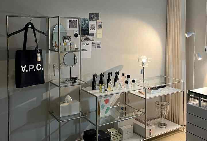 Modern storage space featuring metal and glass shelving and tables against white-toned walls and curtains