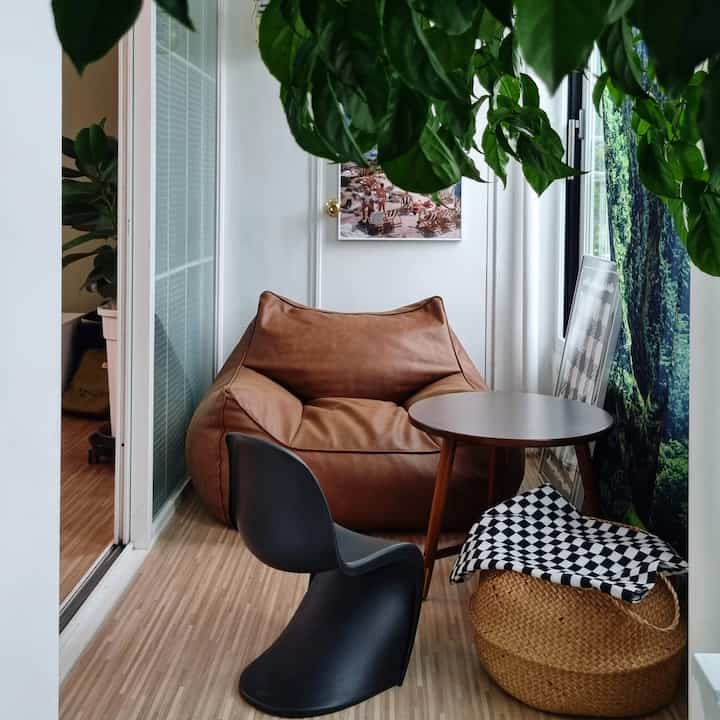 Bright white-toned veranda featuring a brown bean bag, black chair, and rattan basket in a cozy resting area