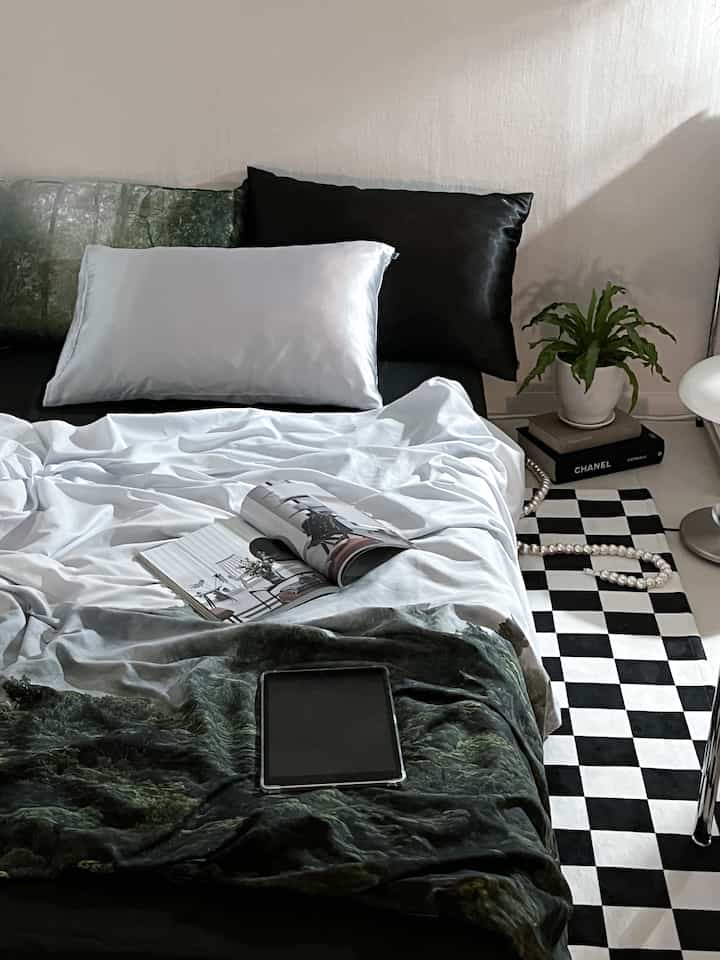 Black and white dominant bedroom featuring checkerboard rug and a plant, creating a modern atmosphere