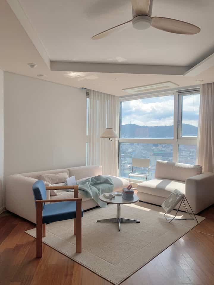 Ivory and natural wood toned living room with large windows allowing abundant natural light in a modern space