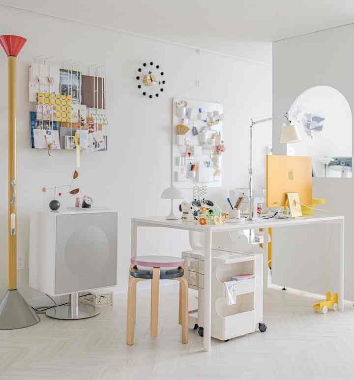 Bright modern home office with white and wood tones, featuring desk, computer, storage, and clean organized setting