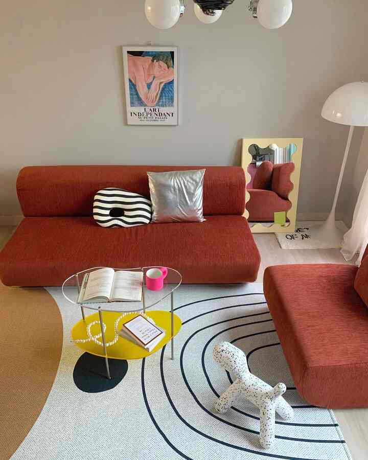 Natural tone living room featuring red Dig sofa, yellow coffee table, patterned rug, and decorative objects in a modern setting
