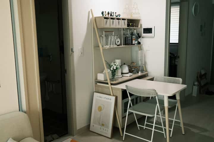 A cozy modern small kitchen and dining area with white and beige tones, featuring a dining table and chairs in a compact space