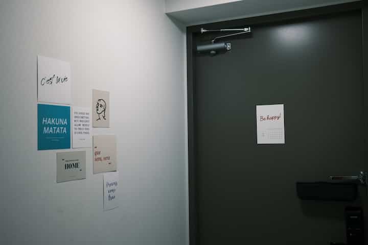 Simple entrance space with gray door and various design posters on white wall to the left