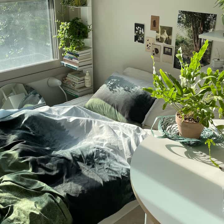 White and green toned bedroom featuring nature-themed bedding and plants, creating a cozy atmosphere