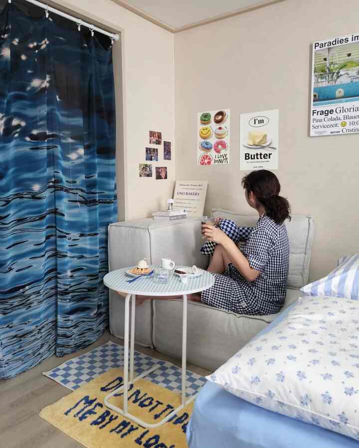 Blue and gray toned bedroom featuring a modular sofa bed and wall posters in a cozy compact space