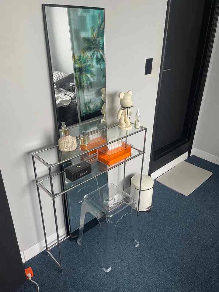 白と黒の調和が取れた韓国インテリアの玄関、広い鏡と透明なアクリルスツールが配されたミニマルで印象的な空間