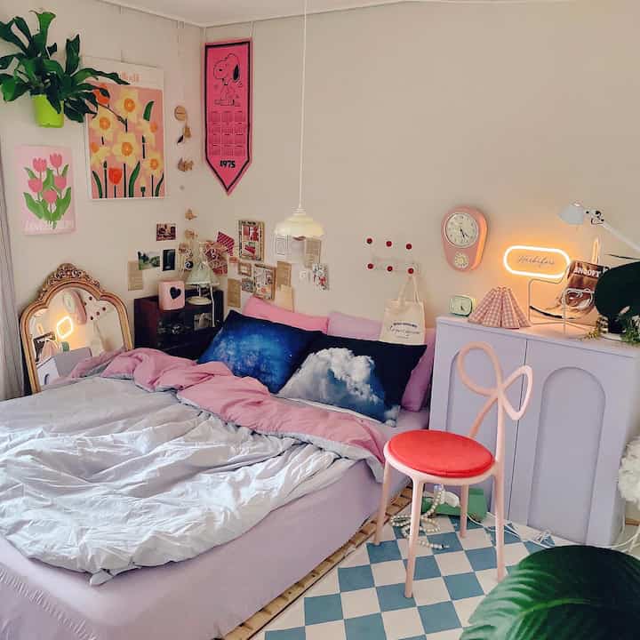 ピンクとブルーの色調の寝室、中央に配置されたベッドと鮮やかな枕と掛け布団カバーが印象的な居心地の良い空間