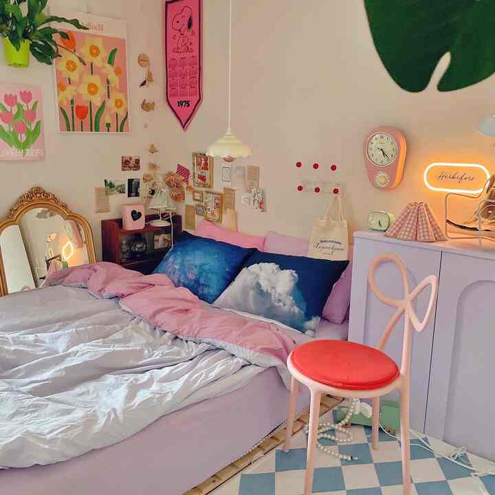 A pink and white toned bedroom featuring a bed with cloud-patterned pillows, checkered rug, unique chair, and whimsical wall decor creating a cozy atmosphere