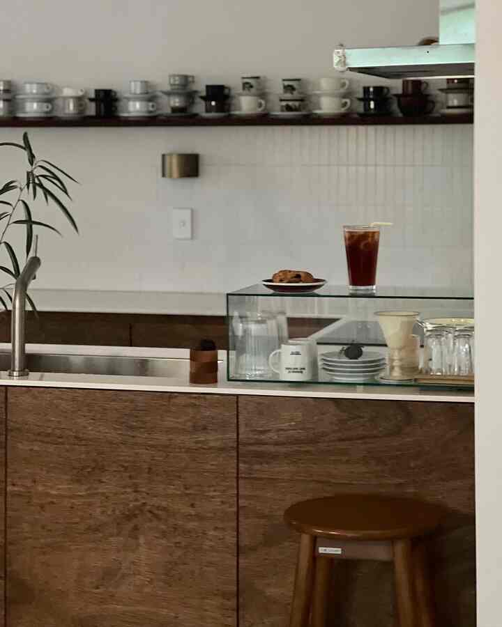 Wood tone cabinetry with white tile backsplash kitchen space featuring iced coffee and cookie for a home cafe