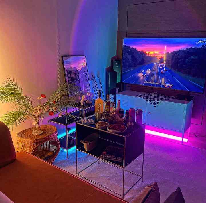 Mood living room under pink and blue neon lights featuring black metal home bar tables and green plants