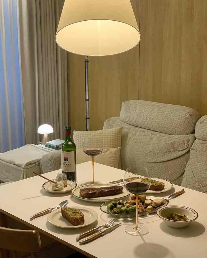 ベージュとホワイトのトーンのリビングルーム、食卓とソファ、フロアランプが配置された雰囲気のあるインテリア