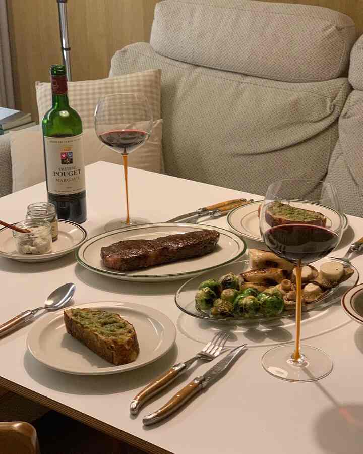 Cozy living room dining table in soft beige and white tones, set with wine glasses and plates, evoking home cafe atmosphere