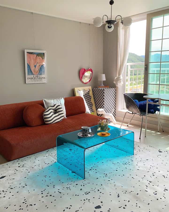 ブラウンのソファと透明なブルーのアクリルテーブルが配置された清涼感のあるリビングインテリア