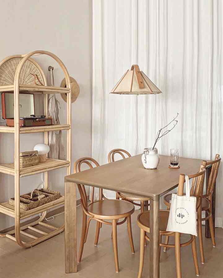 Natural wood tone dining space featuring a 4-person wooden table, rattan shelf, and soft lighting in a warm cafe style
