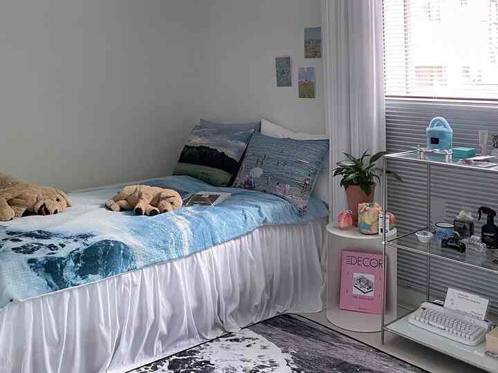 White and blue toned bedroom featuring cozy bed with dog plush toys and cushions beside a small metal rack with accessories