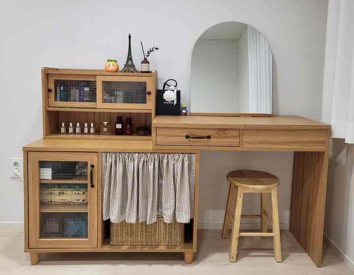 明るい木目調の家具が配置された清潔感のあるパウダールームの化粧台とアーチ型ミラー、木製スツールが置かれた自然な雰囲気のインテリア