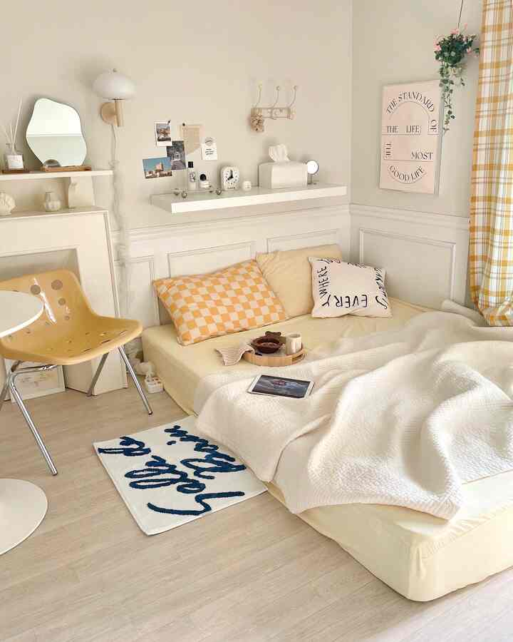 Warm beige and yellow toned bedroom featuring a low mattress and checkered pillow, creating a cozy atmosphere