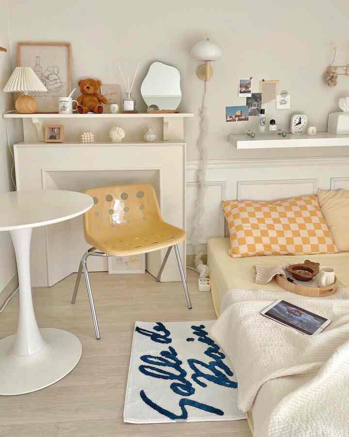 White and natural tone living room featuring a round table, yellow dining chair, fireplace console, and mirror in a cozy setting