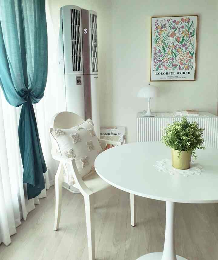 白と緑のトーンのダイニングルーム、白い丸テーブルと椅子、テーブルの上に観葉植物が配置されたシンプルな空間