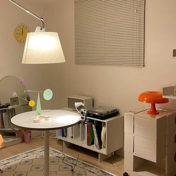 A white and natural tone study featuring Artemide lighting and retro-inspired decor, creating a simple and cozy interior space