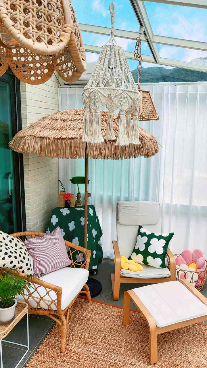 Natural-toned veranda space featuring rattan furniture and parasol lighting with cozy summer interior vibes