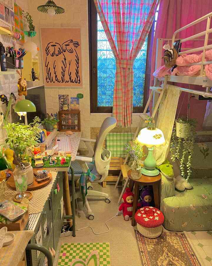 ピンクとグリーンの色調が映える狭いワンルーム、デスク、椅子、二段ベッド、植物が配置された雰囲気のあるホームオフィス