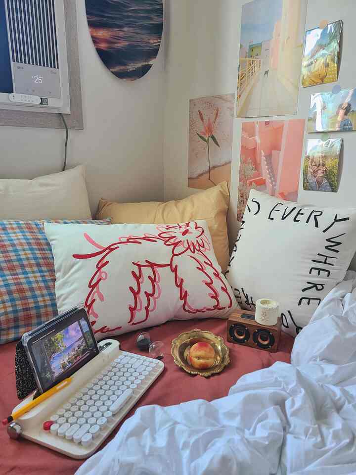 赤みのトーンが主体の寝室、多様なクッションとレトロなタイプライターキーボードが配置された温かみのある居心地の良いインテリア