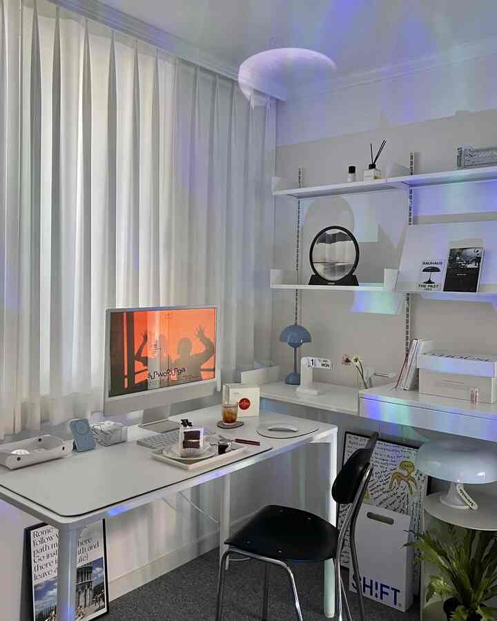 Modern compact home office in white and black tones, featuring an iMac computer and neat desk setup with organized shelves