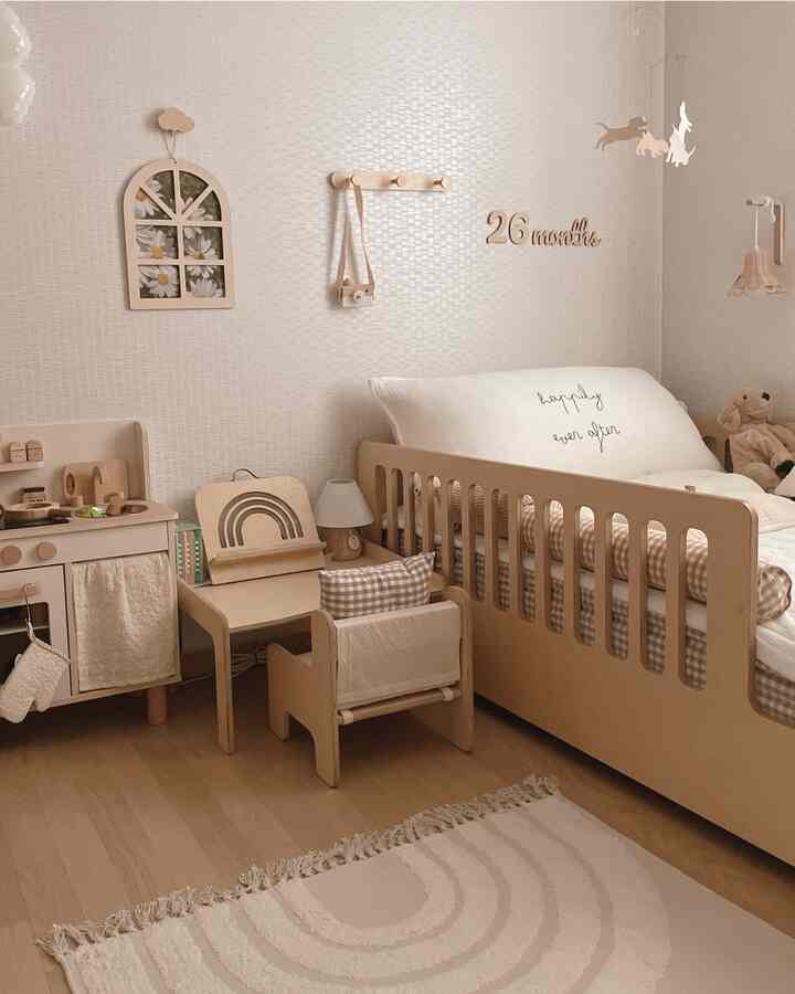 ナチュラルな木目調と白を基調とした子供部屋、ベビーベッドと子供用デスク、ラグが配置された温かみのあるインテリア