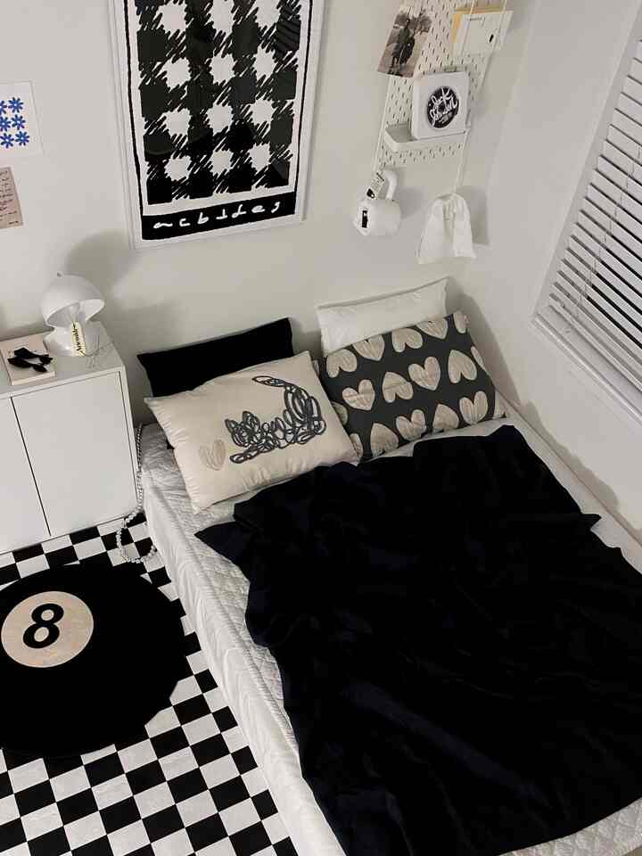 Monotone bedroom featuring white walls, black bedding, and a checkered rug creating a simple and stylish atmosphere