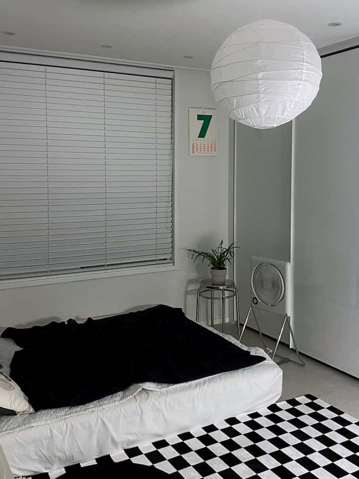 Monochrome white and black 4.5 tatami bedroom featuring a bed and round stools with a modern vibe