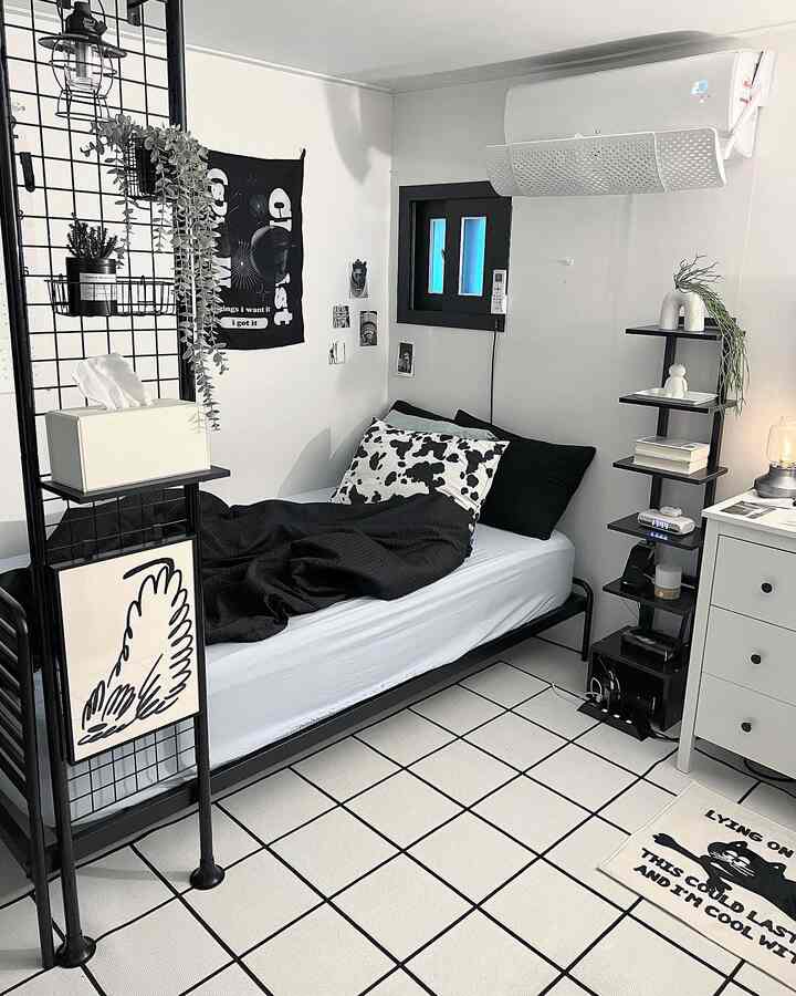 白と黒のトーンでまとめられた寝室、メタルのベッドフレームと寝具、パーティションの間仕切り、棚が配置されたモダンな空間