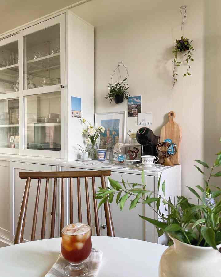 White and wood tone kitchen space featuring wooden chair, vase, and Dolce Gusto coffee machine creating cozy home cafe atmosphere