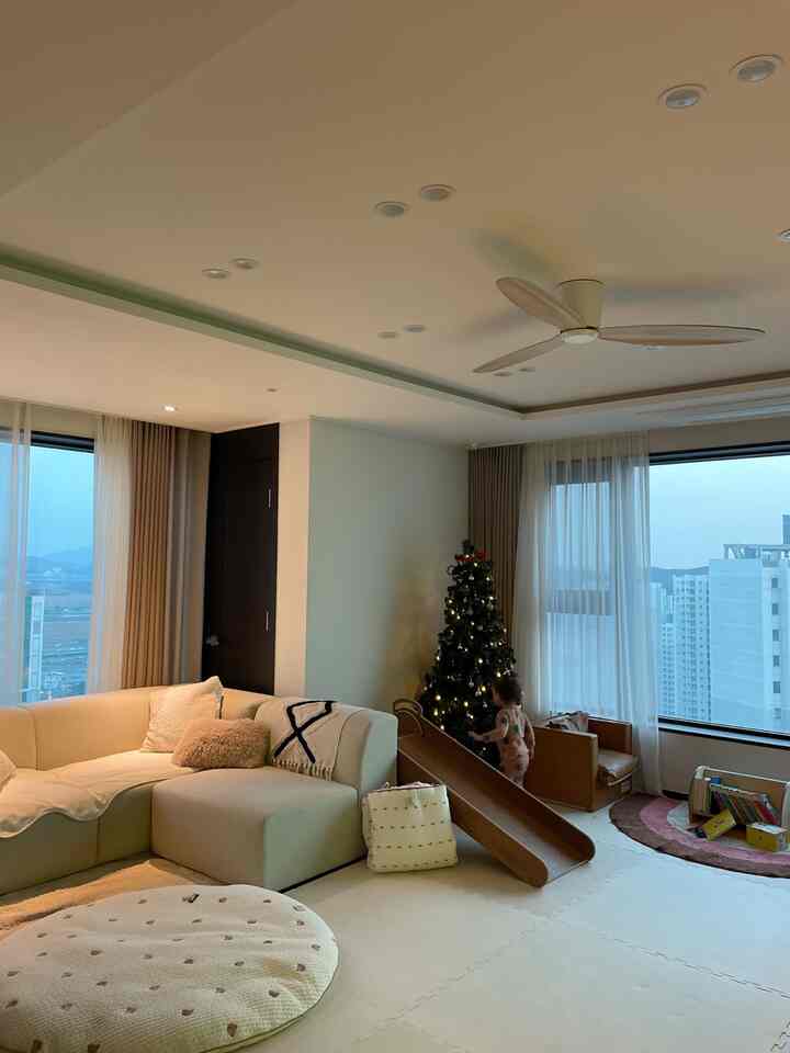 Beige and white toned living room featuring modular sofa, wooden slide, and kid's seating with warm, natural atmosphere