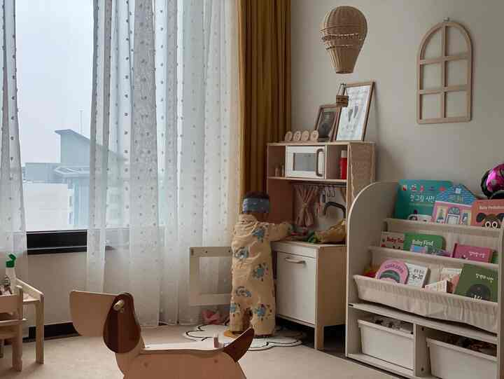 黄色と白を基調とした子供部屋、幼児用ままごとキッチンと絵本棚が配置された印象的な空間