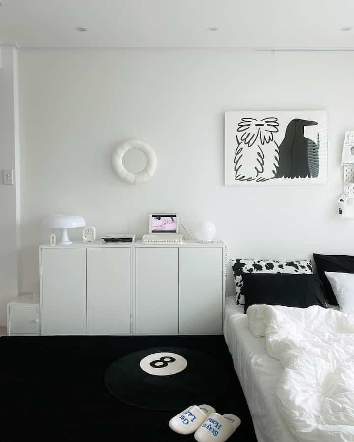 Monotone bedroom in white and black featuring simple dresser, 8-ball rug, and clean minimalist atmosphere