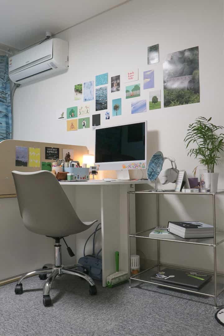 Compact studio home office with white walls, desk, and gray rug, creating a minimal and organized atmosphere